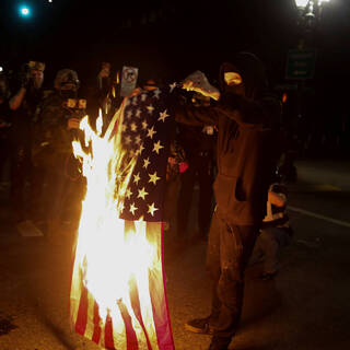 Участник протестов конца сентября в Портленде жжет американский флаг