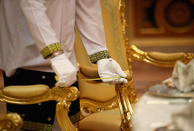 Слуга измеряет расстояние между стульями перед полдником во дворце султана Брунея 