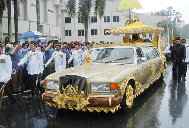 Наследный принц Брунея Аль-Мухтади Биллах и его невеста Сара Пенгиран Саллех проезжают через центр столицы Бандар-Сери-Бегаван на золотом Rolls-Royce после свадебной церемонии, 9 сентября 2004 года