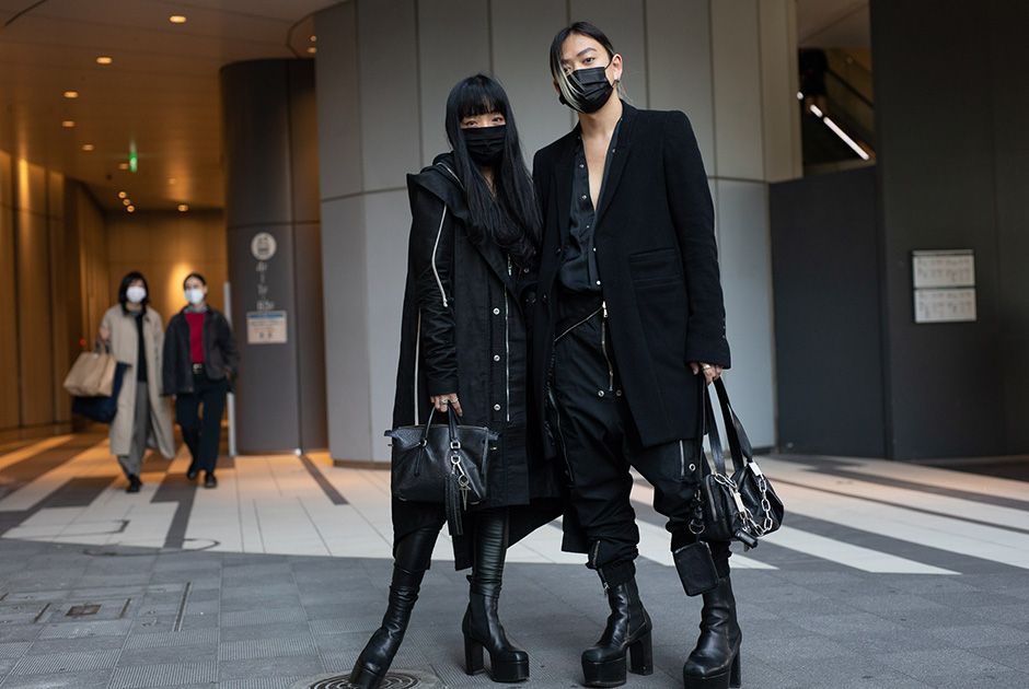 Другие посетители модных событий показали японскую готику с цепями и массивными платформами. Эта пара появилась на улицах Токио, с ног до головы одетой в черные монохромные наряды марки Rick Owens. Черными оказались даже их защитные маски.
