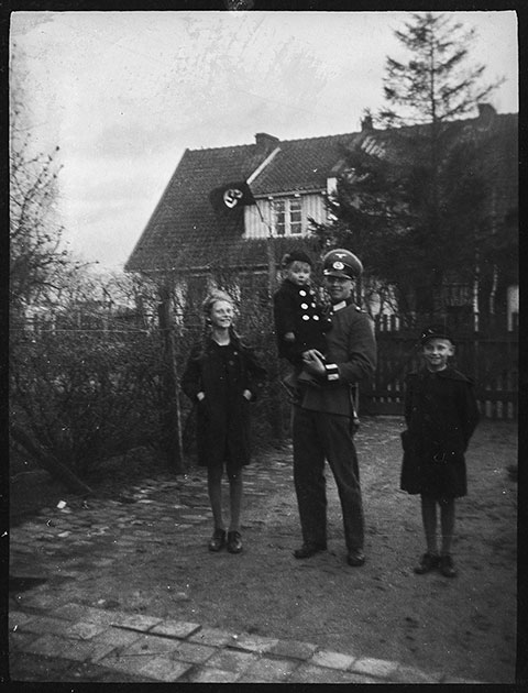 Высокопоставленный сотрудник Имперской службы труда с детьми возле дома с нацистским флагом