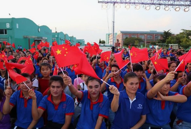 Уйгурские рабочие в учреждении Jiashi Vocational School с китайским флагом