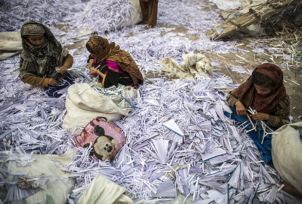 Девятилетняя Разия, одиннадцатилетняя Амна и десятилетняя Саадиа сортируют бумагу, прежде чем отправить ее на переработку в город Лахор, Пакистан