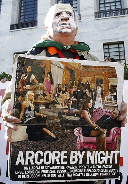 Демонстрант держит плакат с изображением Берлускони у здания Миланского суда во время судебного процесса по обвинению премьера в интимной близости с несовершеннолетней проституткой, 6 апреля 2011 года