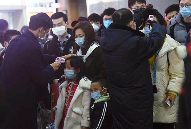Сотрудники вокзала в Ханчжоу измеряют температуру у людей, прибывших на поезде из Уханя