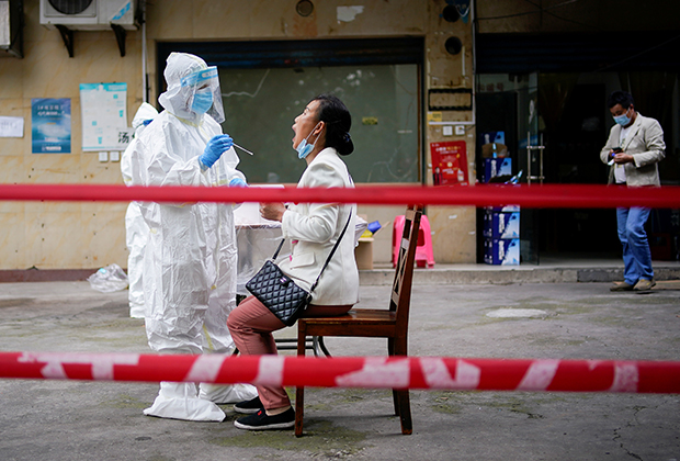 Медработник в защитном костюме делает тест на коронавирус жительнице Уханя