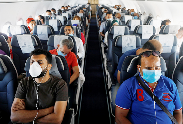 Путешественники в защитных средствах в самолете, вылетающем из Шарм-эль-Шейха