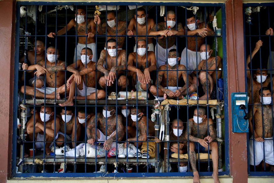 Это члены опасных банд в тюрьме Кесальтепеке в Сальвадоре. Снимок сделан 4 сентября во время пресс-тура, в котором побывал фотограф Reuters Хозе Кабезас (Jose Cabezas). Он впервые увидел преступников из знаменитых группировок MS-13 и Barrio 18.

«В реальном мире они заклятые враги, и исторически в тюрьмах их сажали отдельно, чтобы избежать насилия. Однако в связи с ростом преступлений из-за пандемии коронавируса власти изменили политику и начали смешивать сокамерников из разных банд», — говорит Кабезас. 

«Раньше во время визитов в тюрьму мы видели, как заключенные ходят по территории, но в этот раз атмосфера была иной: бандиты были удивительно тихими и послушными», — вспоминает фотограф. Он смотрел на их лица и замечал, как молоды почти все осужденные. «Старшему из заключенных могло быть 20 с небольшим лет. Для некоторых будет чудом дожить до 30-летнего возраста», — констатировал репортер.