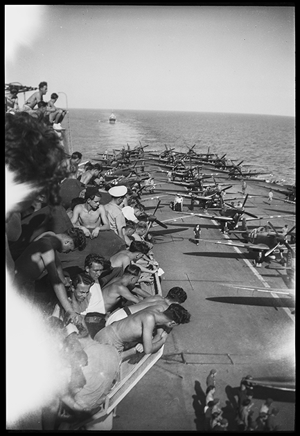 Моряки смотрят на инструктаж пилотов и подготовку палубных истребителей Supermarine Seafire L. Mk. III 887-й эскадрильи перед боевым вылетом с авианосца HMS Indefatigable / «Неутомимый» (R10). Суматра, Индонезия, январь 1945 года.