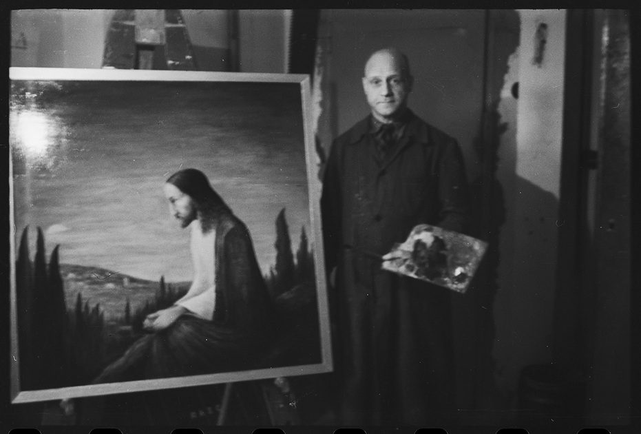 Неизвестный художник в своей студии у картины с изображением Иисуса Христа. Германия, 1945-1950 годы.