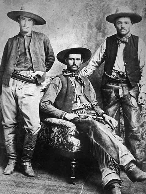 Три техасских ковбоя с ружьями. Жилеты были неотъемлемой частью их костюмов: на брюках не было карманов, а в жилете можно было хранить учетные книги, карандаши, табак или перочинный нож. 1885 год