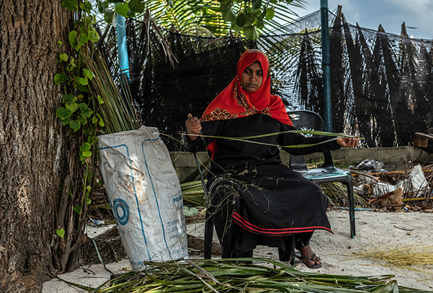 Местная жительница плетет веник из веток