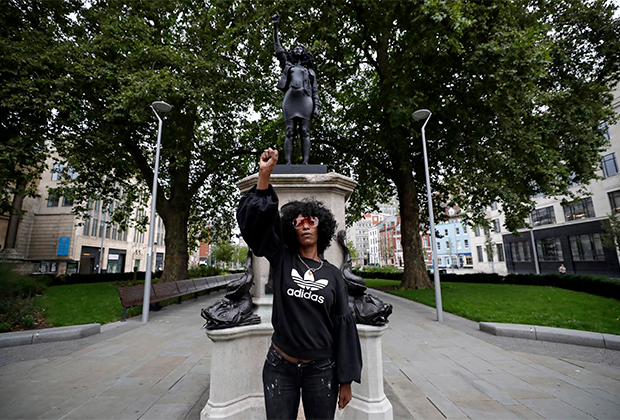 Активистка позирует на фоне статуи, возведенной вместо снесенного памятника работорговцу