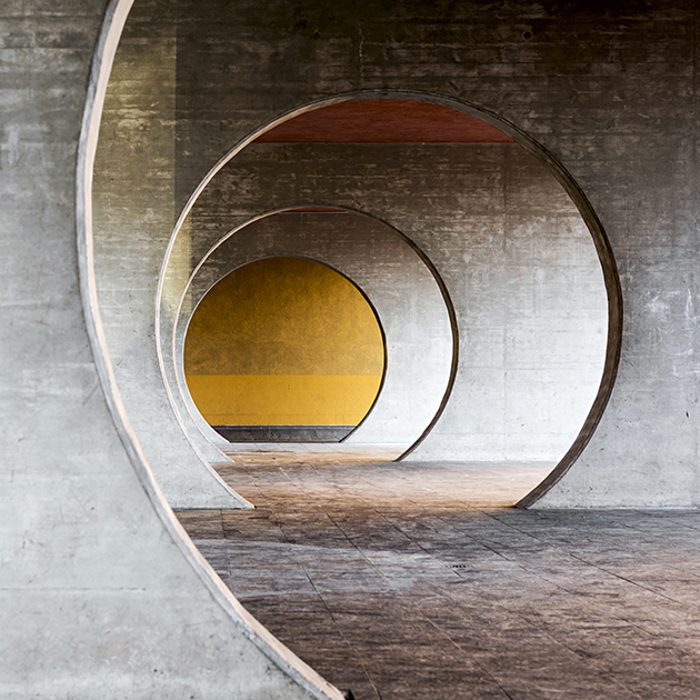 В первой половине 1990-х годов швейцарский архитектор Марио Ботта (Mario Botta) решил изменить представление людей о жилье и придумал комплекс из ста апартаментов в коммуне Новаццано. Особенность строений — четкая геометрия. Ботта использовал в основном прямоугольные формы, но добавил и изгибы. Части соединены крытой галереей с проходами в виде круглых арок. Они образуют гипнотическое пространство тоннеля с идеальной симметрией и ярким акцентом в виде стены, выкрашенной  охрой. Для фасада здания Ботта выбрал лососевый и голубой тона. Кроме жилых помещений в комплексе есть просторный двор и небольшой торговый центр.