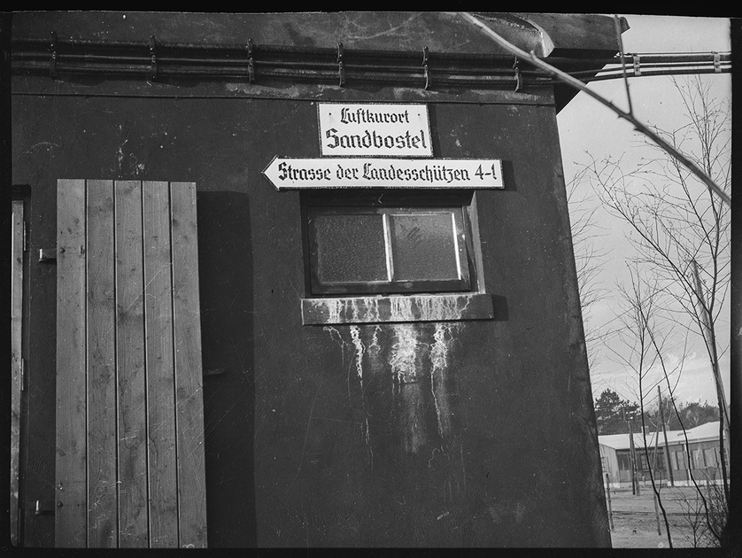 Вывеска на казарме для немецкой охраны шталага Зандбостель: «Климатический курорт Зандбостель. Улица защитников Родины 4-1». Германия, август 1940 — июль 1941 года.

