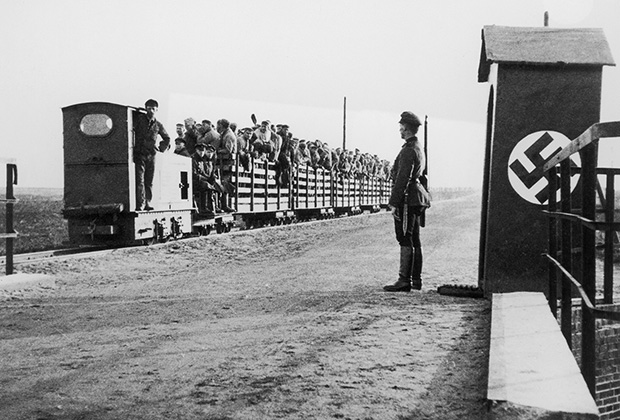 Вооруженный нацистский часовой у поезда, полного людей, на въезде в концлагерь. 1943 год