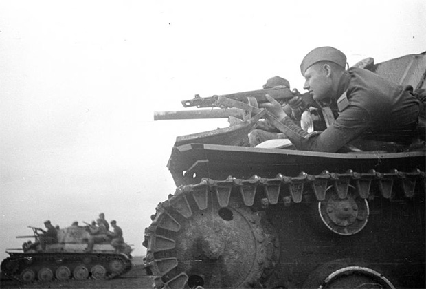 Советский солдат прицеливается из пистолета-пулемета ППШ, лежа на броне танка Т-70