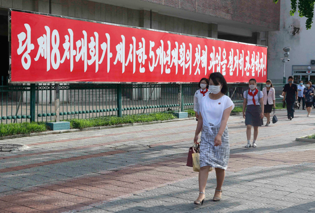Пхеньян. Люди гуляют возле баннера с надписью «Давайте качественно выполним первые задачи пятилетки».