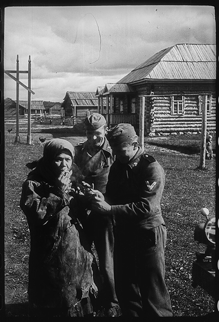 Немецкие танкисты из 7-й танковой дивизии вермахта угощают сигаретой женщину в оккупированной деревне. Белоруссия, СССР, 1941 год.


