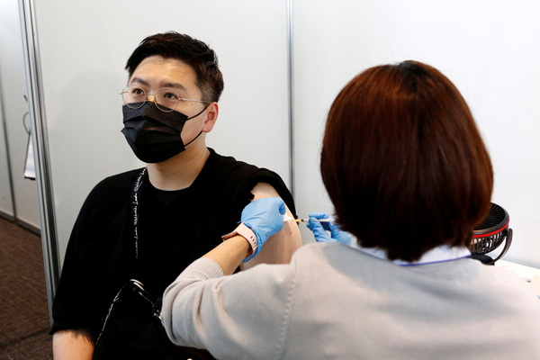 Мужчине делают прививку в Токио