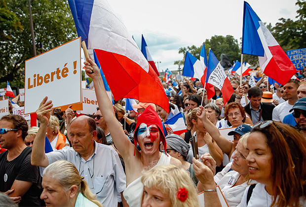 Демонстранты с французскими флагами и транспарантами с надписью «Свободная Франция» во время национального дня протеста против принудительной вакцинации от коронавируса и введения «ковид-паспортов» в Париже, 21 августа 2021 года