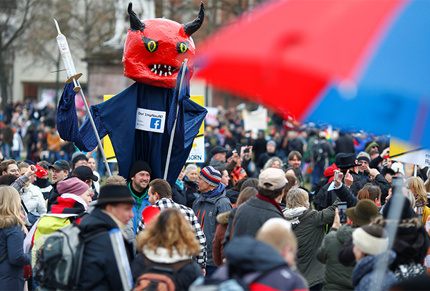 Демонстрант с гигантской марионеткой, изображающей дьявола с вакциной, на акции протеста против правительственных ограничений. Кассель, Германия, 20 марта 2021 года