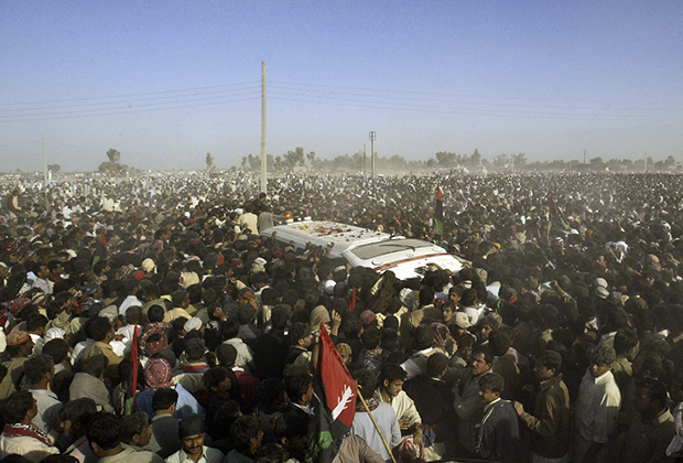 Сторонники убитого лидера оппозиции Беназир Бхутто возле машины скорой помощи, везущей ее тело во время похоронной процессии 28 декабря 2007 года