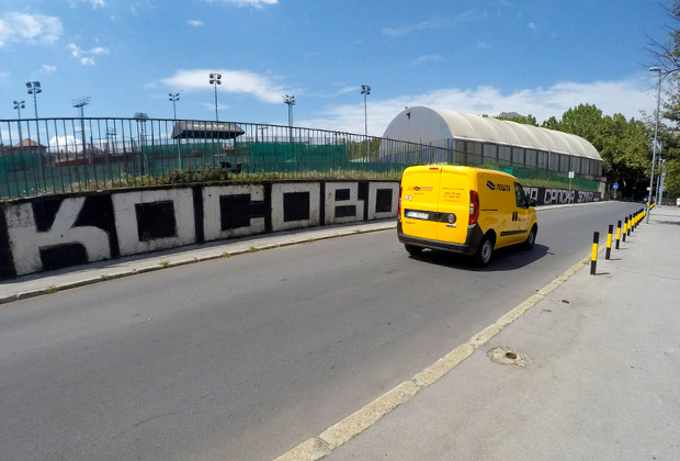 Автомобиль проезжает мимо граффити: «Косово — святая земля Сербии» в Белграде, Сербия