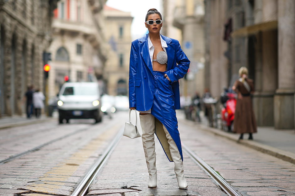 Российская блогерша и стилистка Карина Нигай привлекла внимание фотографов на Неделе моды в Милане ярким нарядом синего цвета. Женщину засняли на улице в кожаных оверсайз-пиджаке и юбке с разрезом, который демонстрировал высокие белые сапоги на каблуке. Еще одной отличительной деталью образа Нигай стал бюстгальтер в стразах, который виднелся из-под расстегнутой белой рубашки. В таком виде она посетила показ итальянского бренда Ermanno Scervino.