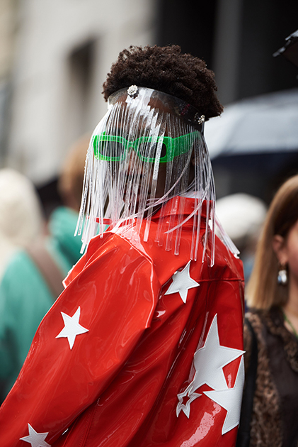 Один из посетителей Недели моды в Париже привлек внимание фотографов своим эпатажным образом. Темнокожего мужчину засняли в ярко-красной лакированной куртке с аппликациями в виде белых звезд на спине и рукавах. Помимо этого, он надел на голову маску из прозрачного пластика с бахромой и солнцезащитные очки в неоновой зеленой оправе.