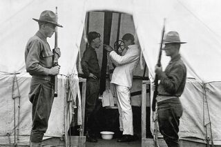 Врач обрабатывает гортань солдата армии США дезинфицирующим раствором во время пандемии испанки. Даллас, штат Техас, декабрь 1918 года