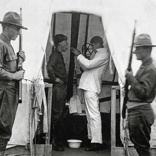 Врач обрабатывает гортань солдата армии США дезинфицирующим раствором во время пандемии испанки. Даллас, штат Техас, декабрь 1918 года
