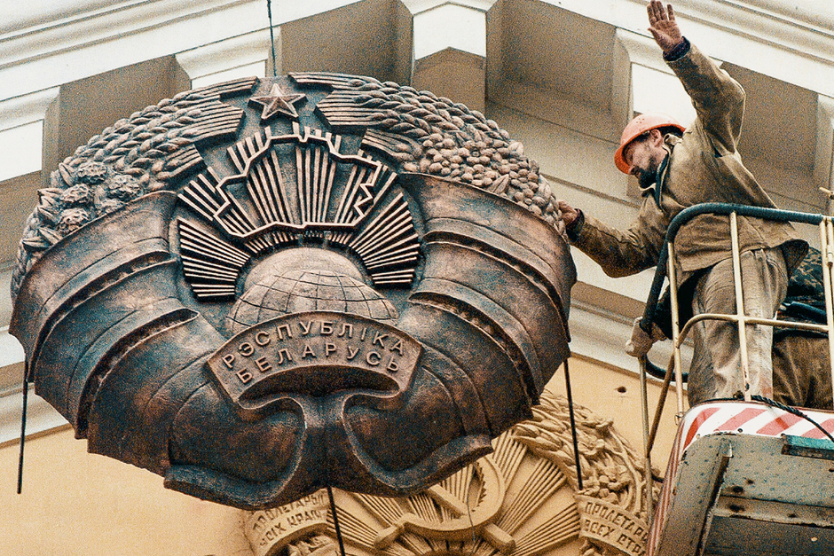 Рабочий устанавливает новый герб на фасаде здания Комитета государственной безопасности Белоруссии в центре Минска, 21 ноября 1996 года 
