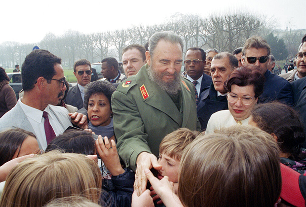 Фидель Кастро в окружении телохранителей пожимает руки детям во время обзорной экскурсии по Парижу. 14 марта 1995 года