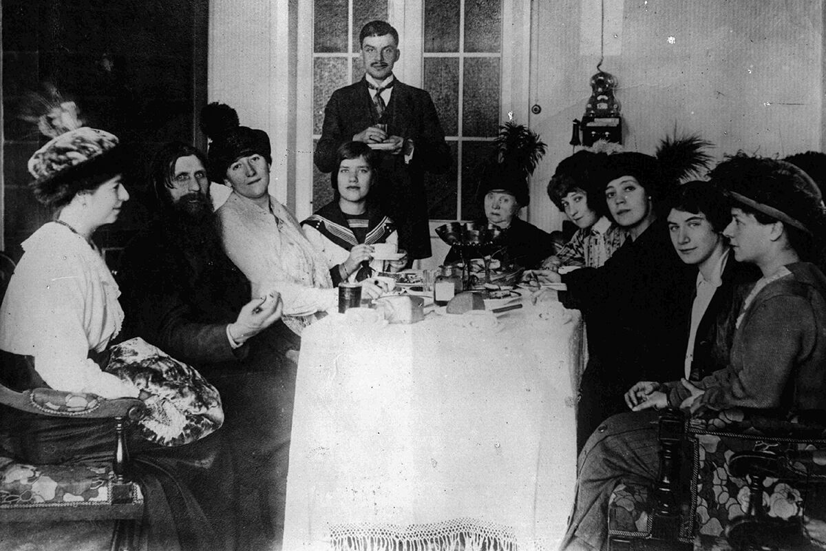 Григорий Распутин с женой Прасковьей Федоровной Дубровиной (третья слева), дочерью Матреной Григорьевной Распутиной (четвертая слева) и поклонниками в своей квартире. Санкт-Петербург, 1911 год