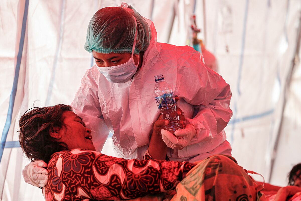 Медработник и пациентка во временной палатке, установленной из-за нехватки коек в государственной больнице, Индонезия, 15 июля 2021 года
