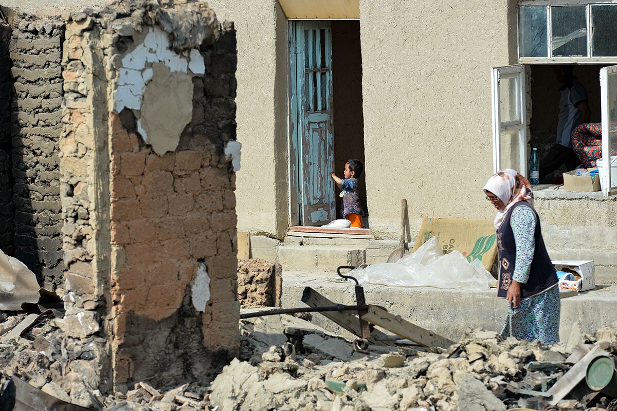 Киргизская женщина идет через руины своего дома в селе Максат, неподалеку от границы с Таджикистаном, 4 мая 2021 года