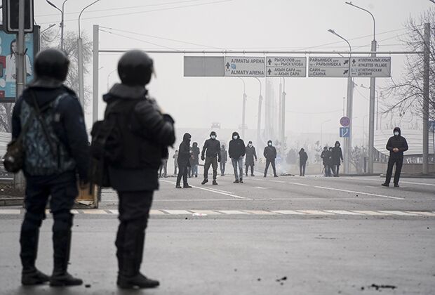 Демонстранты стоят перед полицейскими во время акции протеста в Алматы, Казахстан, 5 января 2022 года