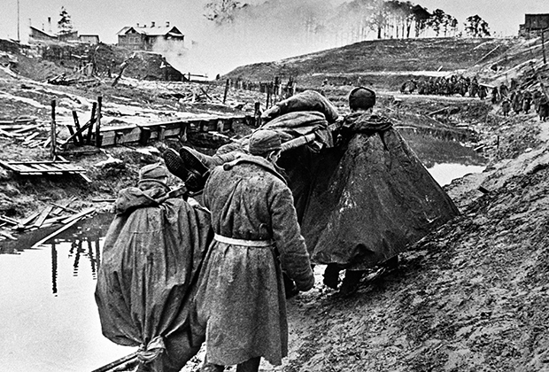 Бойцы выносят раненого с поля боя на Невской Дубровке (на противоположном берегу — Невский пятачок), октябрь 1941 года