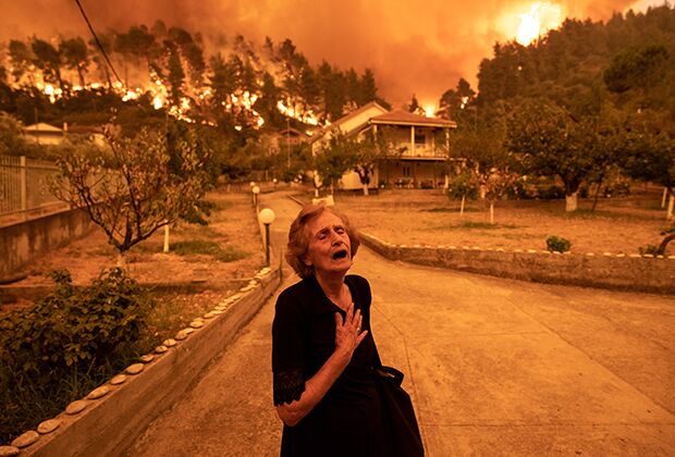 Пожилая дама покидает свой дом, которому угрожает лесной пожар, в деревне Гувес на острове Эвия, Греция 