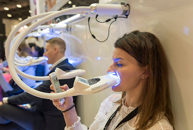 Посетители салона красоты тестируют способ отбеливания зубов, Лондон, 2019 год