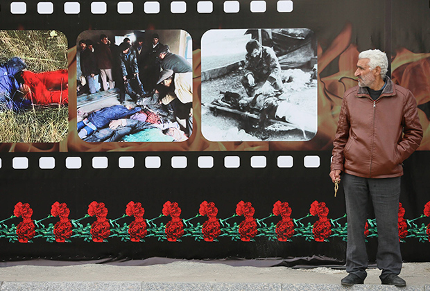 Мужчина стоит перед портретами во время церемонии, посвященной 24-й годовщине Ходжалинской трагедии