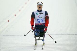Алексей Быченок финиширует в мужском биатлоне на 7,5 км сидя во время Паралимпийских зимних игр 2014 года в Сочи