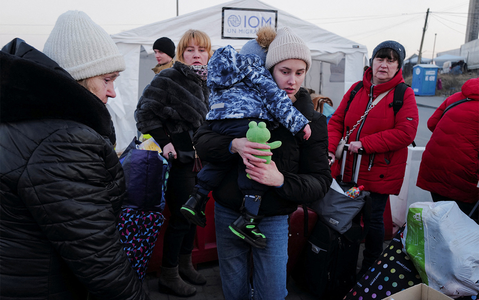 Беженцы с Украины стоят в очереди, чтобы сесть в автобус после пересечения границы с Польшей на пограничном пункте в Медыке, 13 марта 2022 года