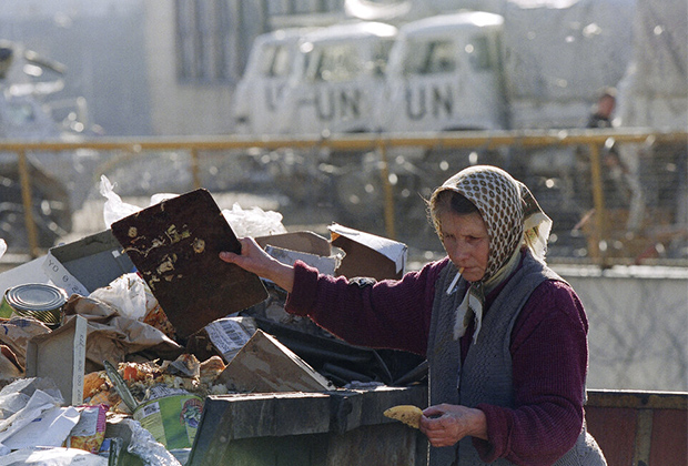 Женщина вынимает кусок хлеба из мусорного бака рядом с французской базой миротворцев ООН в центре Сараева, 4 апреля 1995 года
