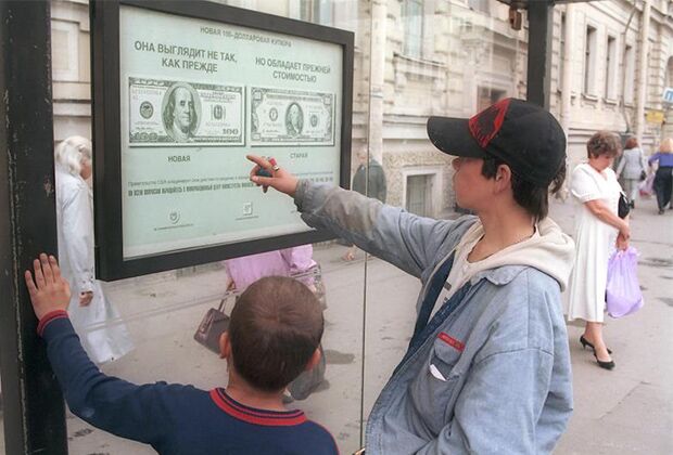 Дети-беспризорники у стенда с изображением нового доллара на улице Санкт-Петербурга, 90-е годы