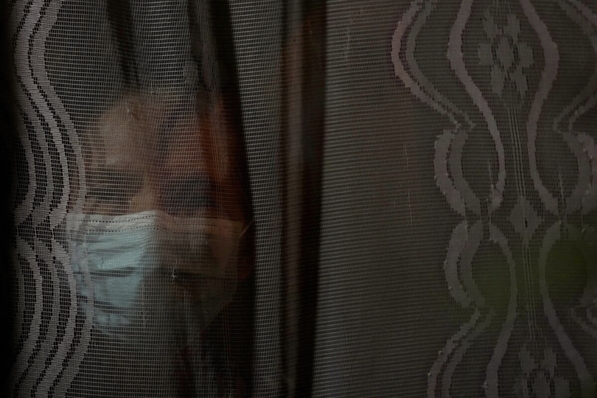 Наталисия Гонсалвес, 77-летняя учительница на пенсии, выглядывает из окна своего дома в районе Пиньейру