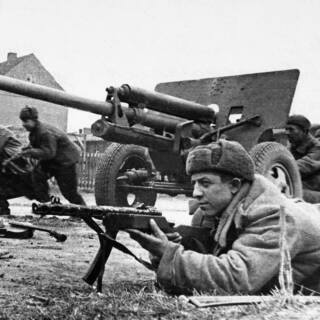Советские артиллеристы у 57-мм противотанкового орудия ЗиС-2 и бойцы штурмовой группы ведут уличный бой за Кенигсберг, апрель 1945 года