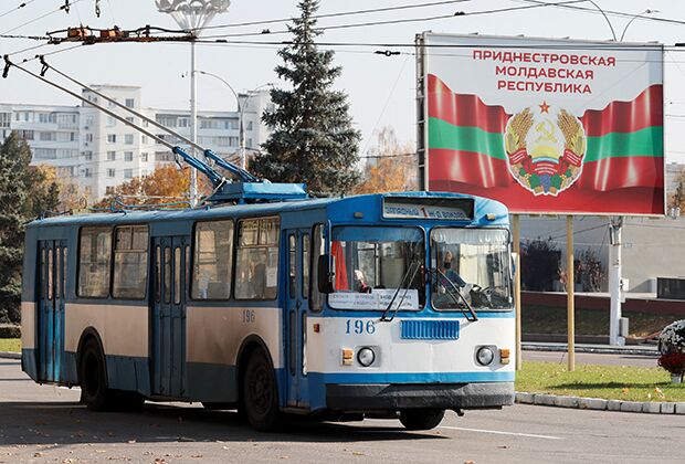 Троллейбус проезжает рядом с билбордом, на котором изображен официальный герб ПМР, 3 ноября 2021 года