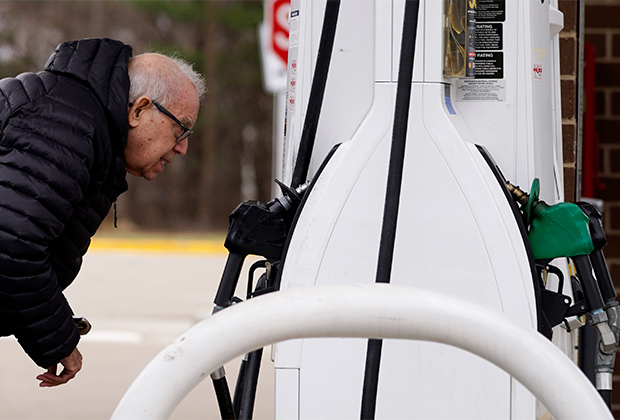 Мужчина смотрит на цены на бензин на заправочной станции в штате Иллинойс, 26 марта 2022 года